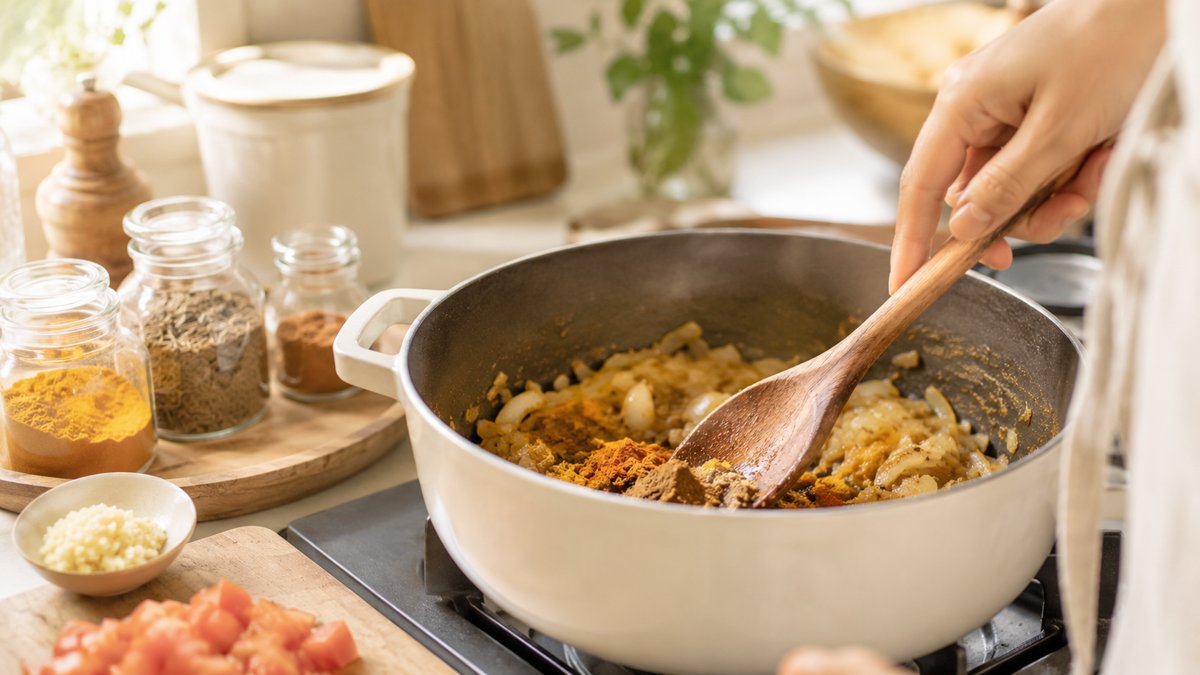 玉ねぎやスパイスを使ってカレーを作っている調理シーン